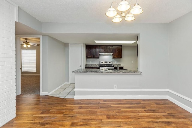 kitchen featuring light wood-type flooring, dark brown cabinetry, a textured ceiling, and electric range