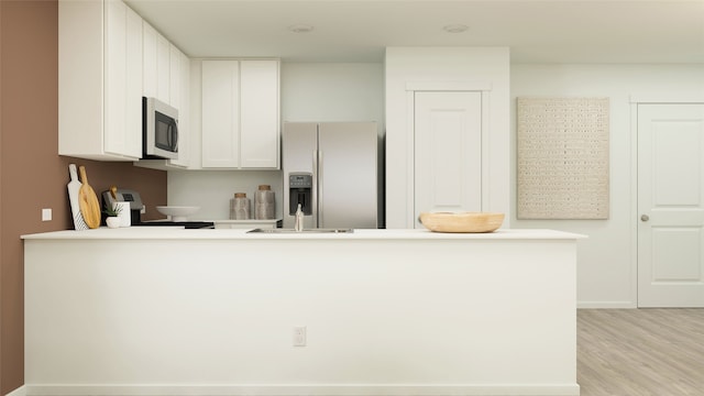 kitchen with light wood-style floors, stainless steel appliances, light countertops, white cabinets, and a peninsula