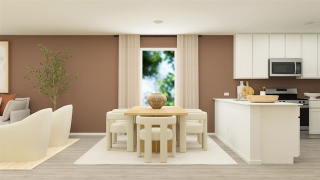 kitchen with light wood finished floors, baseboards, white cabinets, and stainless steel appliances