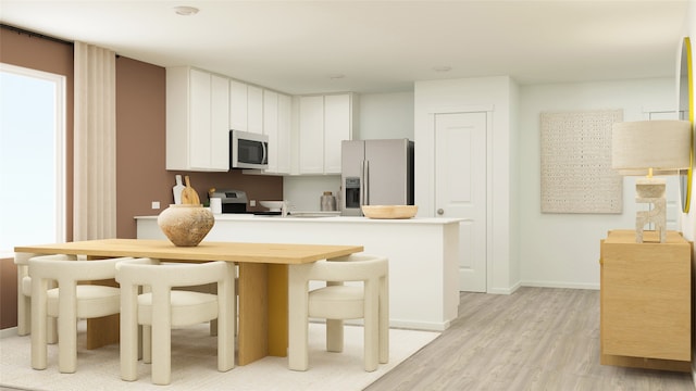 kitchen with white cabinets, light countertops, a peninsula, stainless steel appliances, and light wood-style flooring