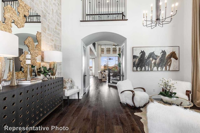 14509 Capridge Rd, Aledo, TX 76008 - hallway featuring wood finished floors, arched walkways, a towering ceiling, baseboards, and a notable chandelier