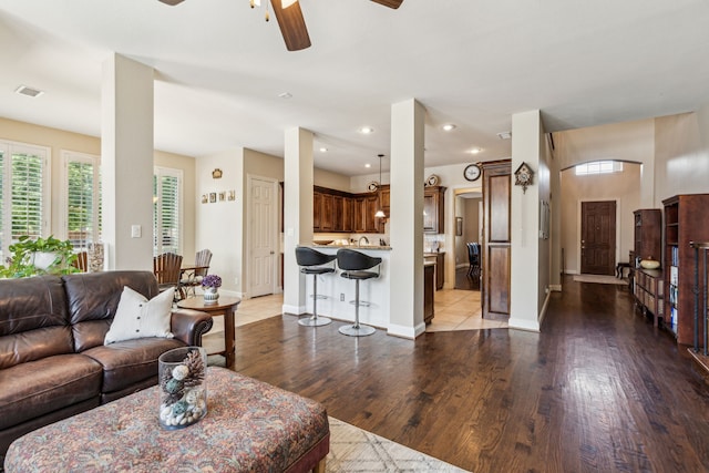 living area featuring a ceiling fan, wood finished floors, visible vents, and a healthy amount of sunlight