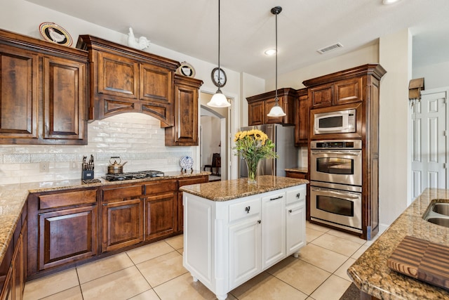 kitchen featuring light stone counters, tasteful backsplash, stainless steel appliances, decorative light fixtures, and white cabinets