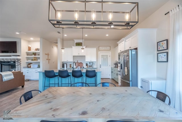 dining room featuring built in shelves, recessed lighting, a brick fireplace, and light wood-type flooring