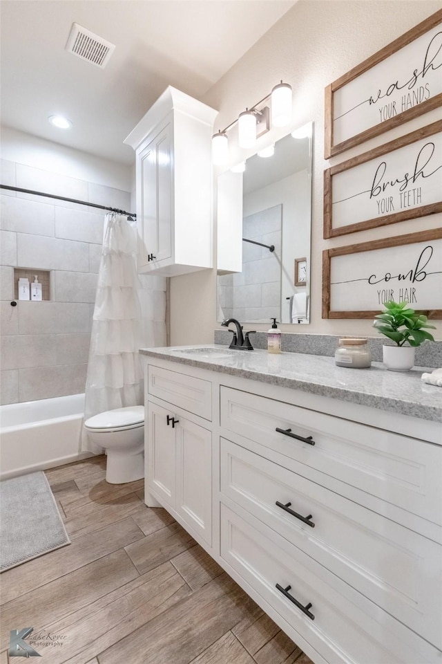 bathroom featuring wood finished floors, vanity, shower / bathtub combination with curtain, toilet, and visible vents