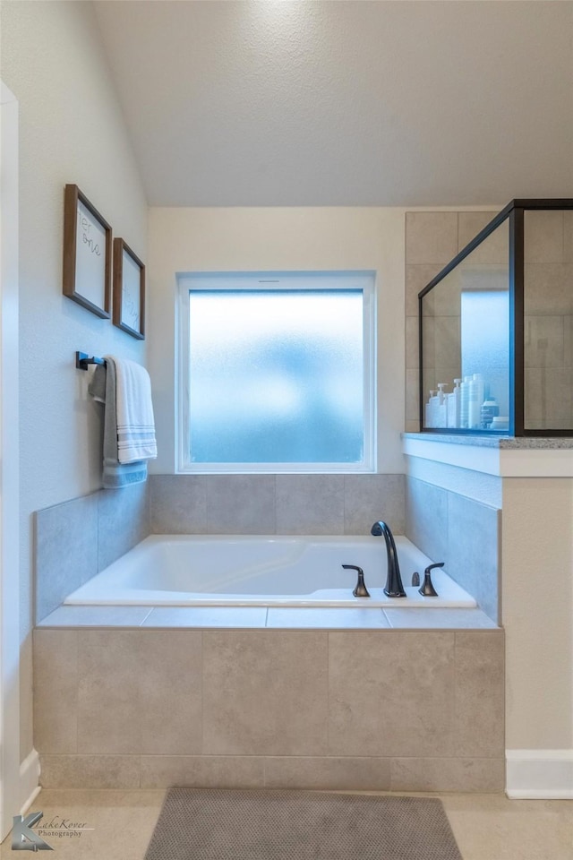 full bath featuring vaulted ceiling, a bath, and tiled shower