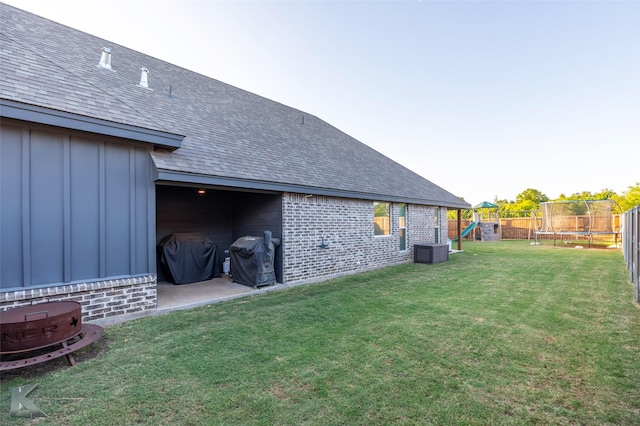 exterior space featuring a patio area, a playground, a trampoline, central air condition unit, and a fenced backyard