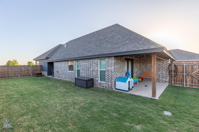 rear view of house with a fenced backyard, brick siding, a patio, and a shingled roof