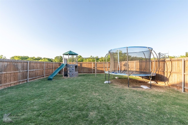 view of jungle gym with a yard, a trampoline, and a fenced backyard