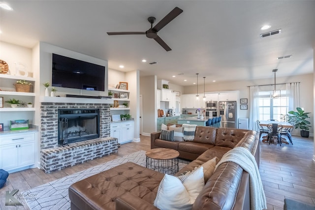 living room with light wood-type flooring, visible vents, and a ceiling fan