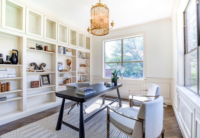 home office featuring a wainscoted wall, dark wood-style floors, ornamental molding, a decorative wall, and a notable chandelier