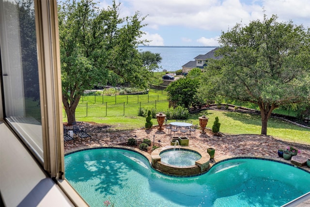 view of pool with a patio, a pool with connected hot tub, a water view, fence private yard, and a lawn