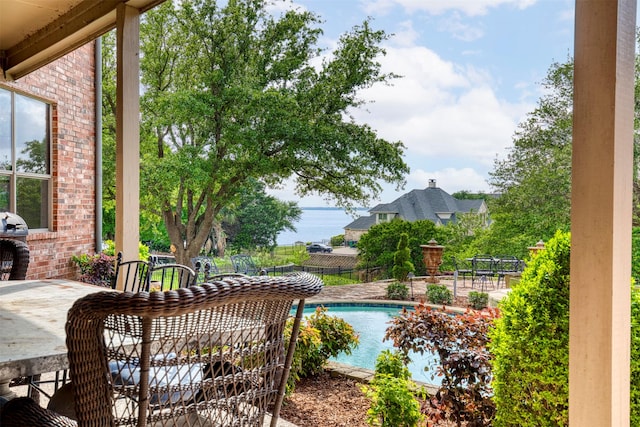 pool with fence, a water view, and a patio