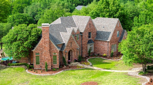 view of front of home featuring a front lawn, brick siding, and a chimney