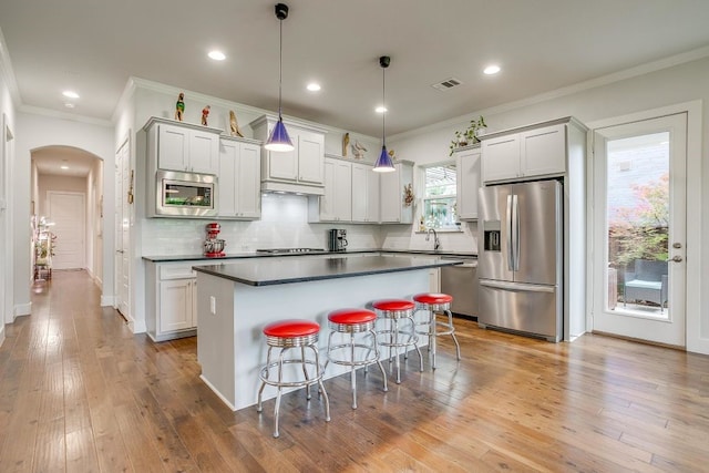 1833 Crested Ridge Rd, Fort Worth, TX 76008 - kitchen featuring a center island, dark countertops, crown molding, arched walkways, and appliances with stainless steel finishes
