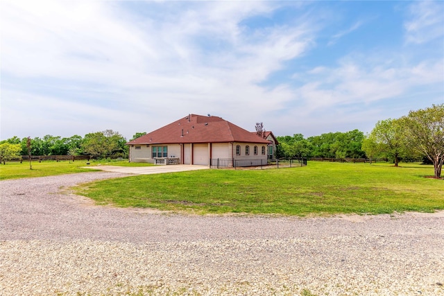 exterior space with an attached garage, gravel driveway, a lawn, and fence private yard