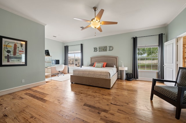 bedroom with wood finished floors, crown molding, baseboards, and multiple windows