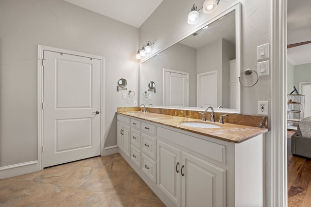 bathroom with double vanity, baseboards, and a sink