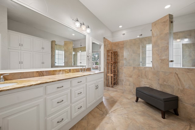 bathroom with double vanity, walk in shower, a healthy amount of sunlight, and a sink
