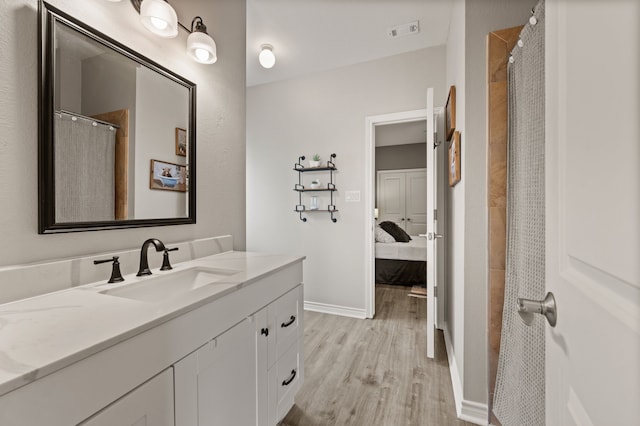 full bathroom with wood finished floors, vanity, baseboards, ensuite bath, and visible vents
