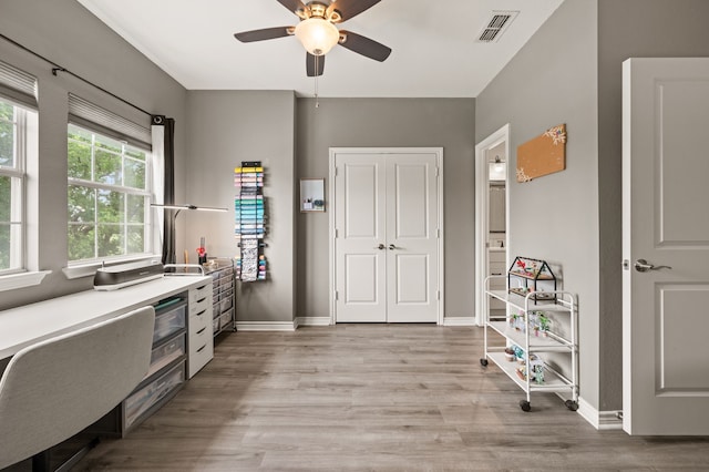 office area featuring baseboards, a ceiling fan, visible vents, and light wood-style flooring