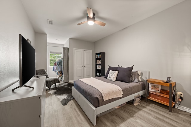 bedroom featuring light wood-style flooring, baseboards, visible vents, a closet, and ceiling fan