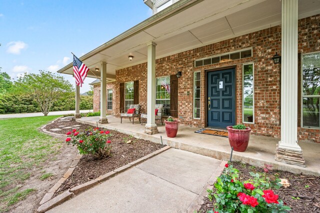 doorway to property with brick siding and a porch