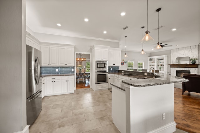 kitchen featuring crown molding, tasteful backsplash, open floor plan, stainless steel appliances, and a fireplace