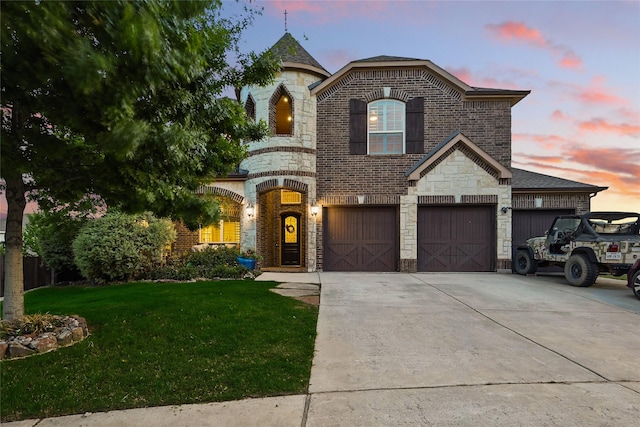 french country inspired facade with a front lawn, driveway, stone siding, fence, and brick siding