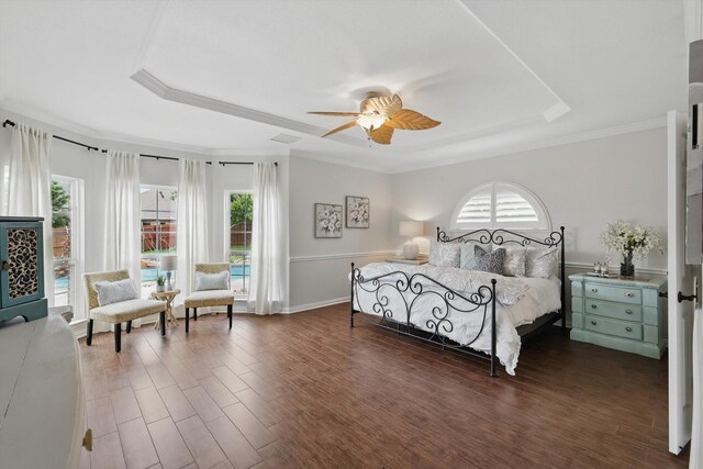 bedroom with ceiling fan, dark wood-style flooring, ornamental molding, and a tray ceiling