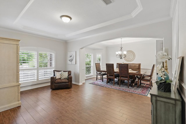 dining room featuring a wainscoted wall, a tray ceiling, ornamental molding, dark wood-style flooring, and a notable chandelier