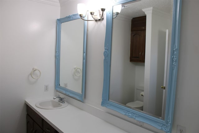 bathroom featuring a textured ceiling, vanity, an inviting chandelier, toilet, and ornamental molding