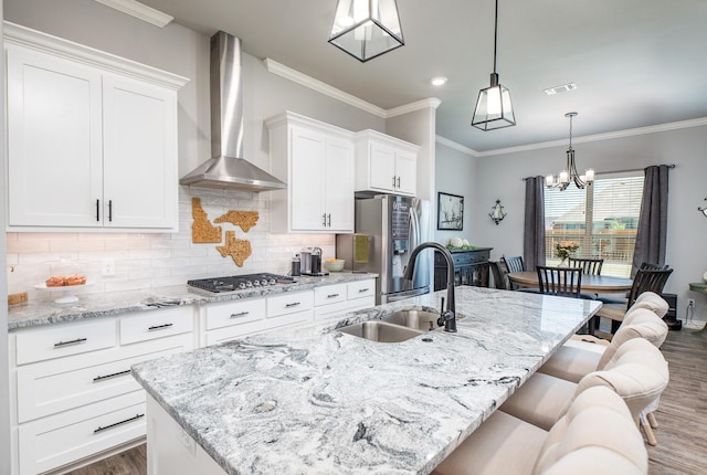 kitchen with wall chimney range hood, a sink, stainless steel appliances, a center island with sink, and dark wood-style floors