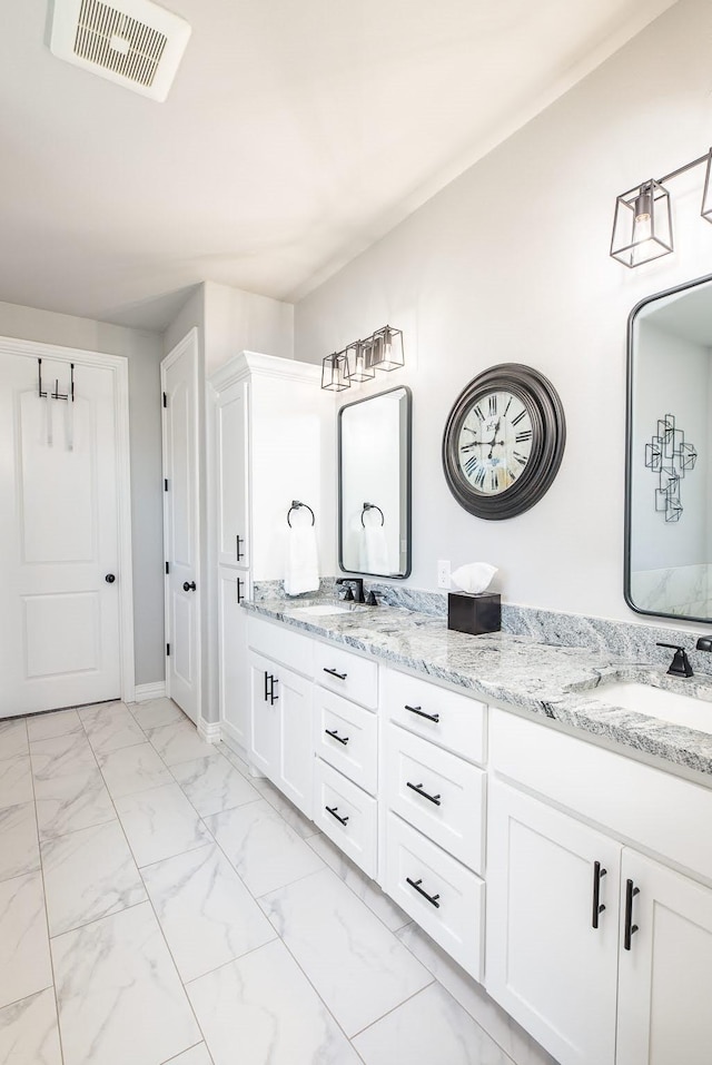 full bath featuring marble finish floor, double vanity, visible vents, a sink, and baseboards