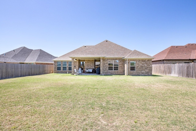 rear view of property featuring a fenced backyard, brick siding, and a lawn