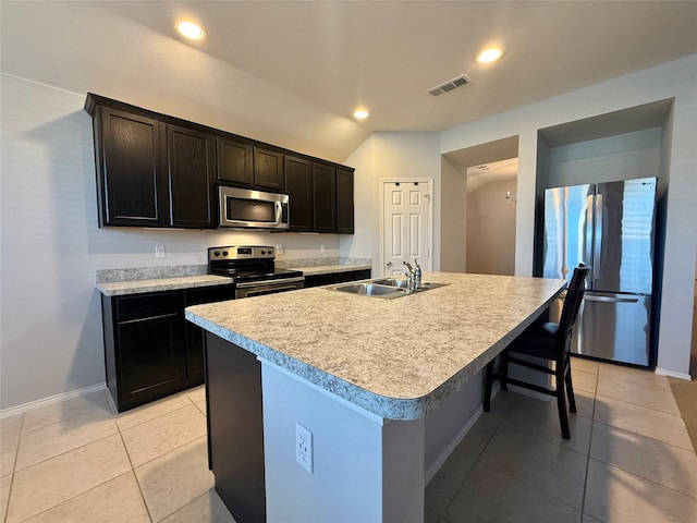 1131 Grimes Dr, Forney, TX 75126 - kitchen featuring appliances with stainless steel finishes, light tile patterned floors, light countertops, a breakfast bar area, and an island with sink