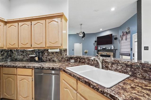 kitchen with dark countertops, dishwasher, light brown cabinetry, and a sink