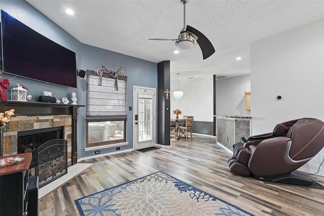 107 Princeton Cir, Forney, TX 75126 - living room featuring a ceiling fan, wood finished floors, a textured ceiling, recessed lighting, and a stone fireplace