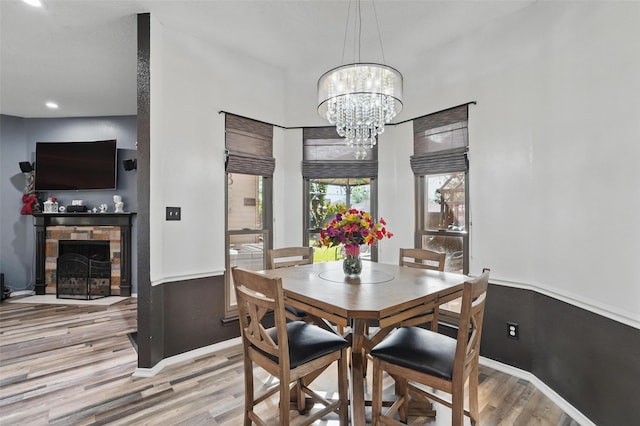 dining room with baseboards, recessed lighting, a notable chandelier, wood finished floors, and a stone fireplace