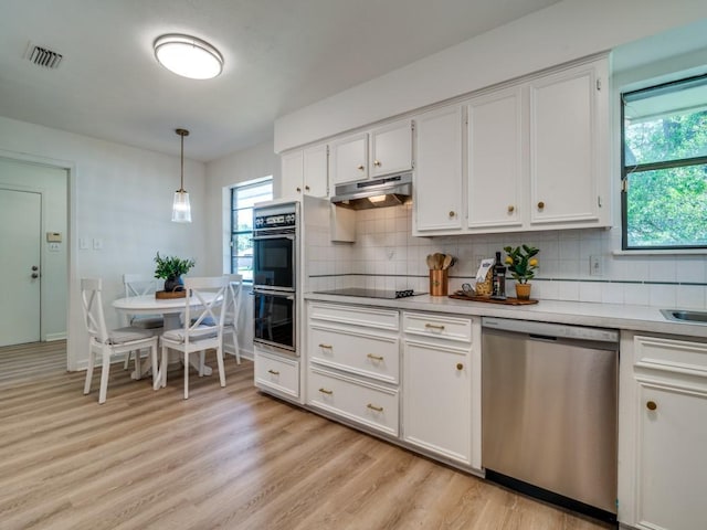 kitchen featuring white cabinets, under cabinet range hood, light wood-style floors, black appliances, and tasteful backsplash