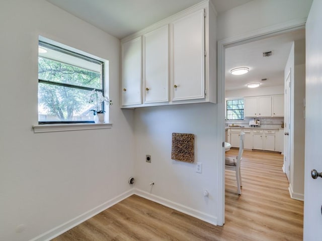 washroom with light wood finished floors, visible vents, hookup for an electric dryer, hookup for a gas dryer, and cabinet space