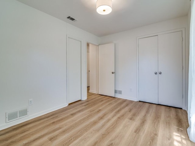 unfurnished bedroom featuring baseboards, wood finished floors, and visible vents
