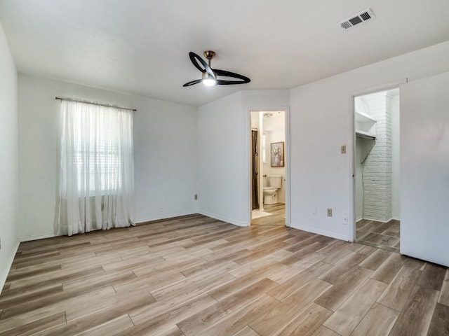 unfurnished bedroom with visible vents, light wood finished floors, baseboards, and connected bathroom