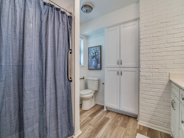 full bath with a shower with curtain, toilet, baseboards, wood finished floors, and vanity