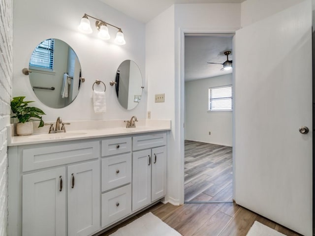 full bathroom featuring a ceiling fan, wood finished floors, a sink, and double vanity