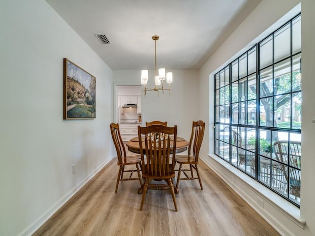 dining room featuring light wood-style floors, visible vents, baseboards, and a notable chandelier