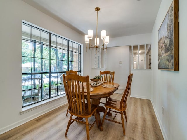 dining room featuring baseboards, wood finished floors, an inviting chandelier, and a healthy amount of sunlight
