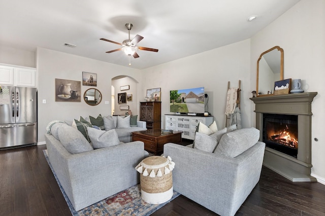 2452 Open Range Dr, Fort Worth, TX 76177 - living area with arched walkways, a ceiling fan, a glass covered fireplace, and dark wood-style flooring