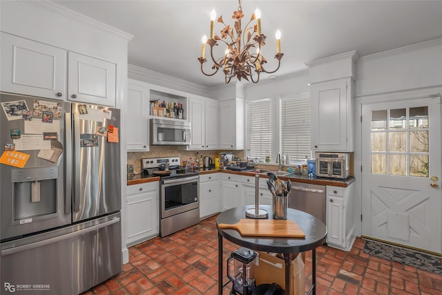 kitchen featuring stainless steel appliances, brick flooring, a sink, a chandelier, and decorative backsplash