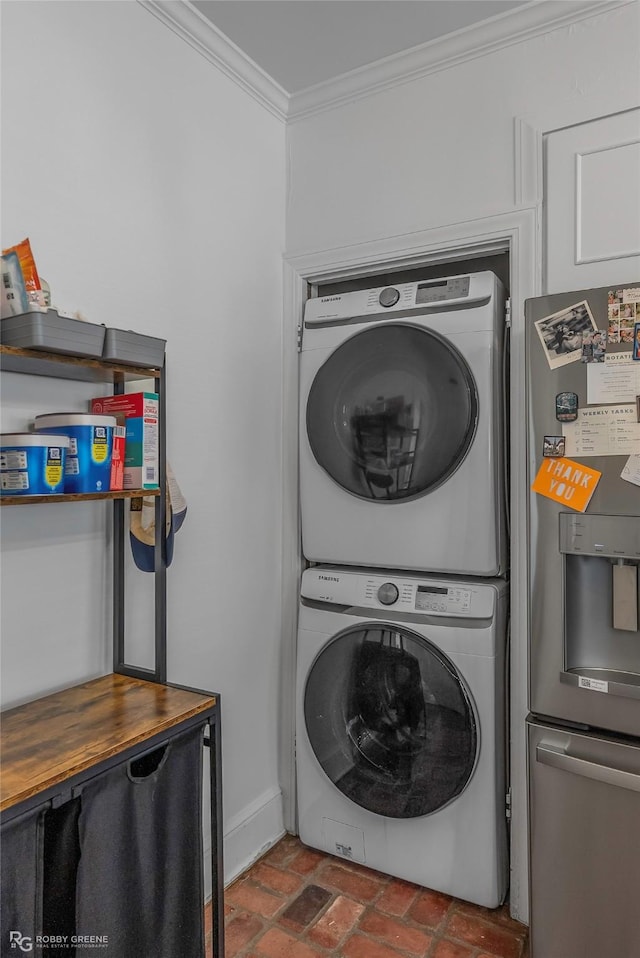 laundry area with brick flooring, stacked washer and clothes dryer, crown molding, and baseboards
